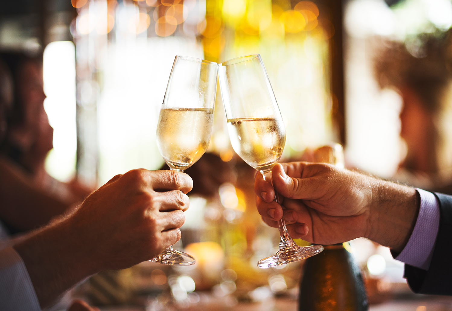 Zwei Gläser Sekt werden in einem festlichen Ambiente beim Romantik-Hof Greetsiel angestoßen und gefeiert.