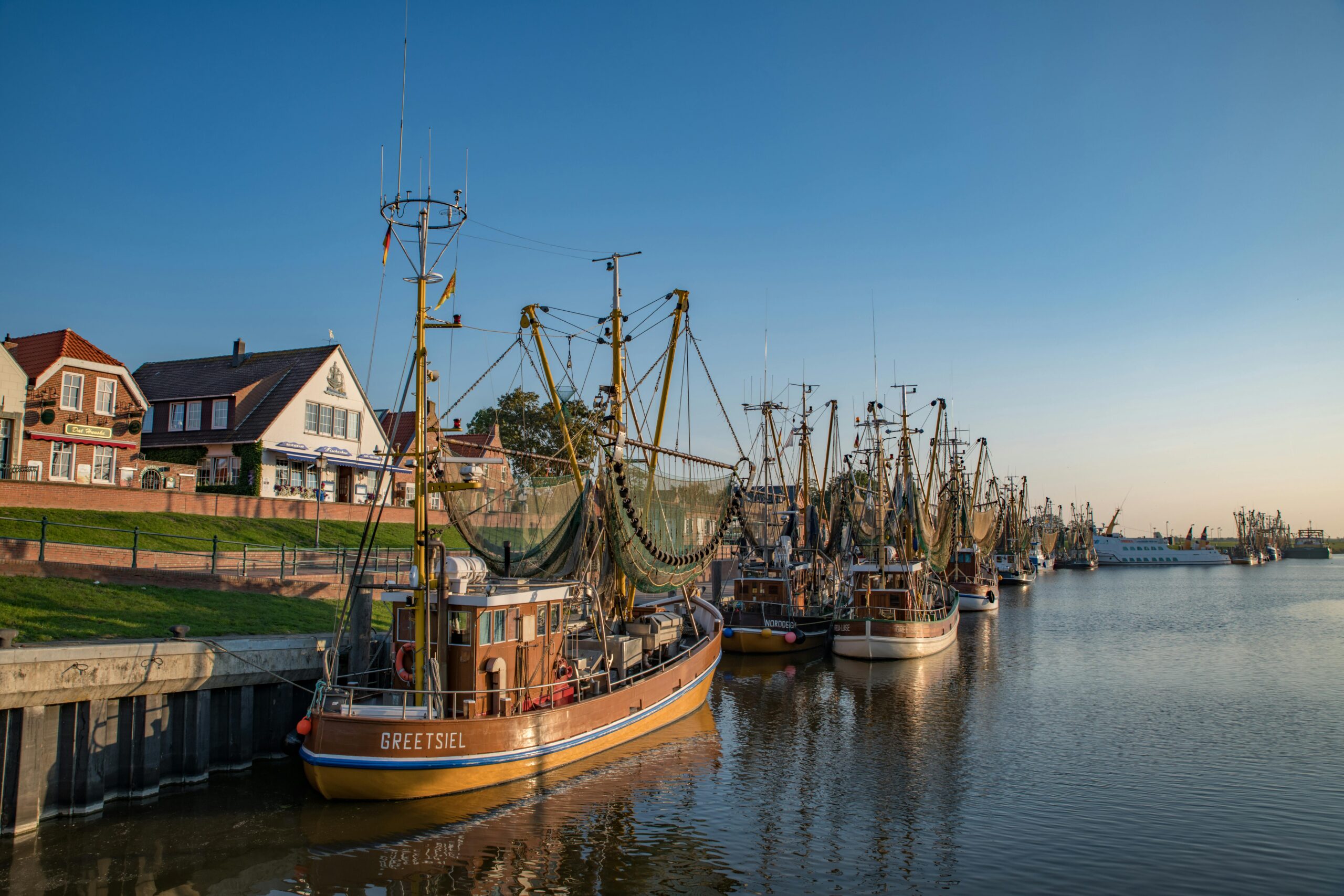 Blick auf den Hafen von Greetsiel mit traditionellen Fischkuttern und charmanten Häusern am Ufer.